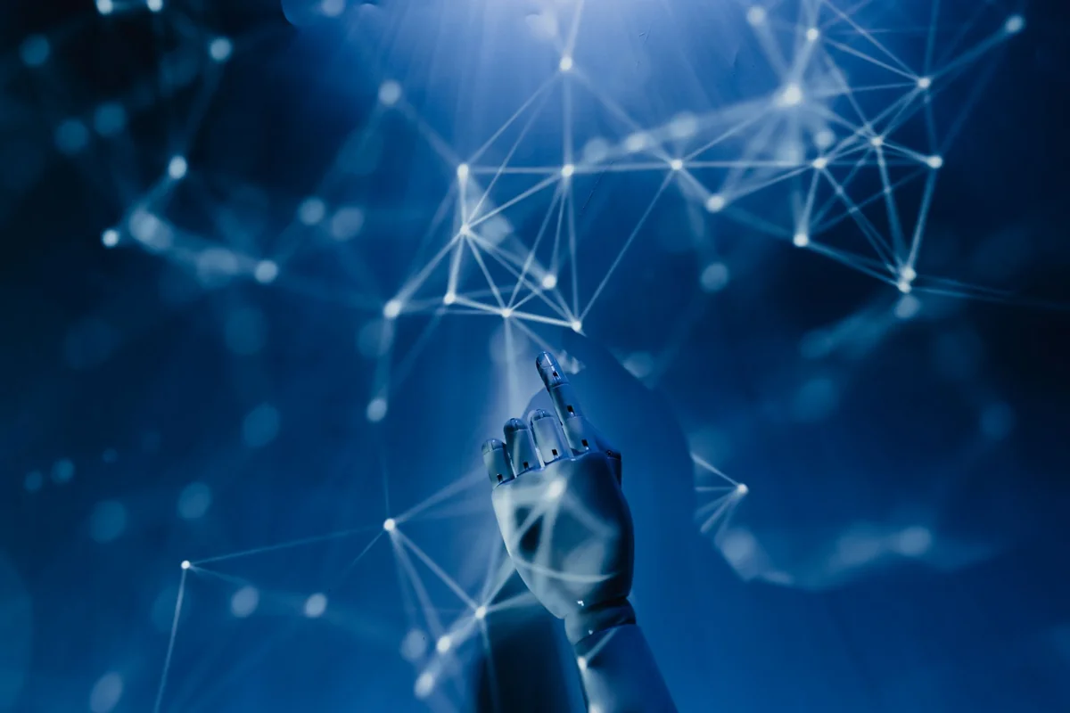 A robotic hand reaching into a digital network on a blue background, symbolizing