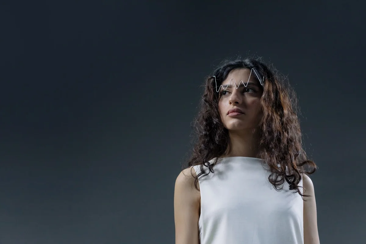 Studio portrait of a woman with curly hair and abstract eyewear, serene expressi