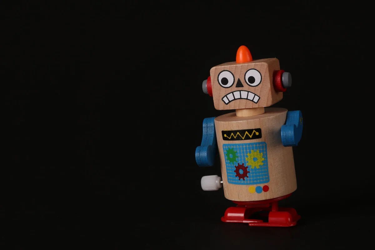 A vibrant wooden toy robot stands on a dark surface, showcasing vivid colors and