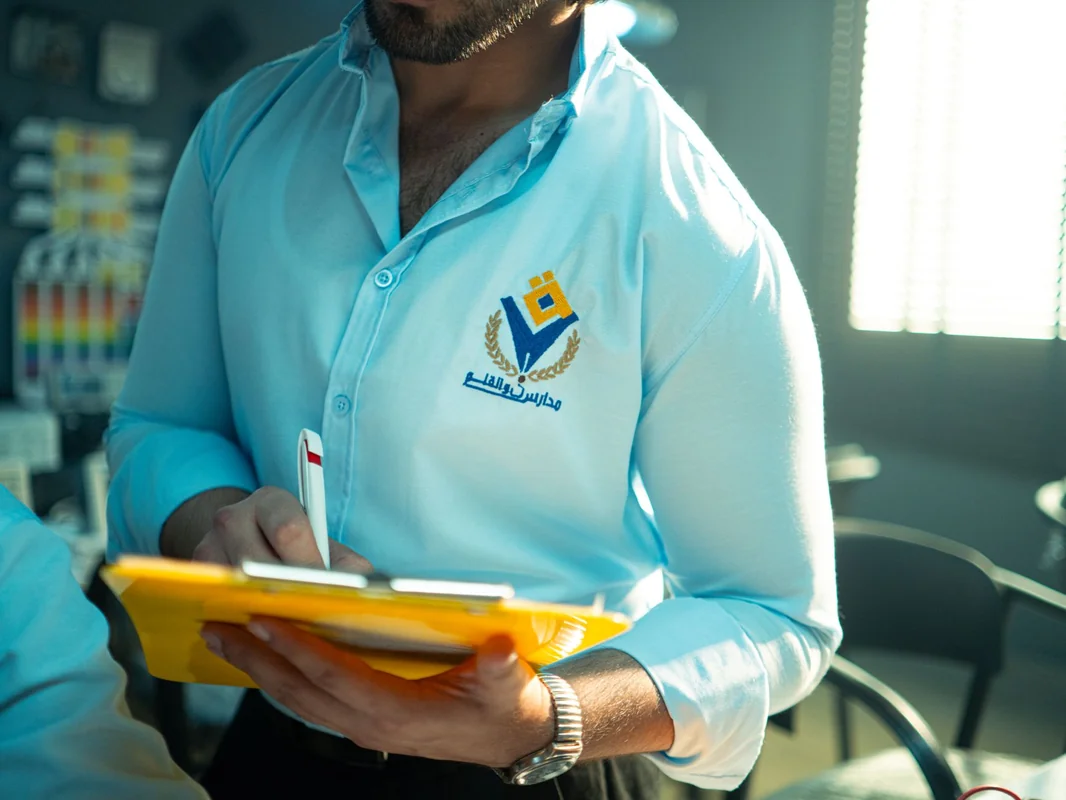 Man in professional attire holding a yellow notepad and pen in an office setting