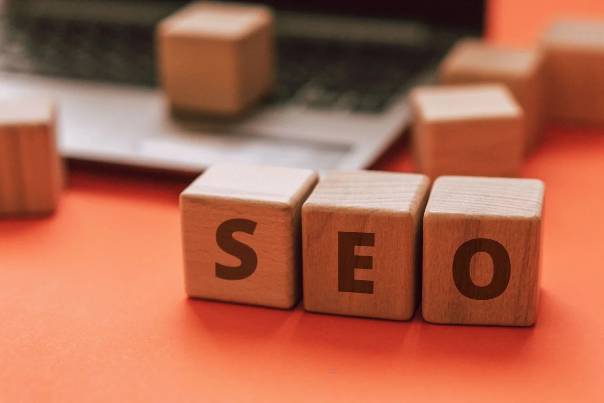 Wooden blocks spelling SEO on a laptop keyboard convey digital marketing concept