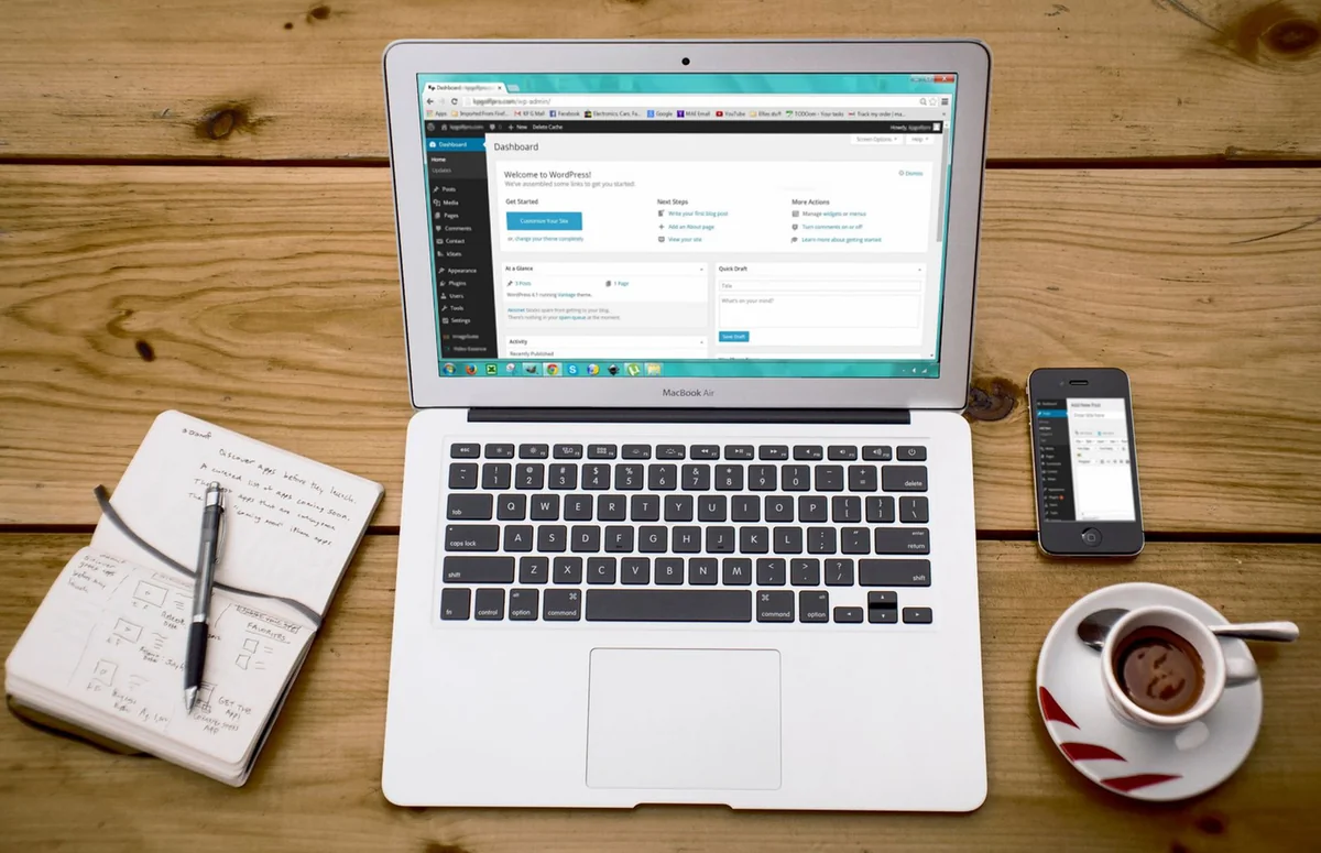 A cozy home office scene with a laptop, notebook, smartphone, and coffee, perfec