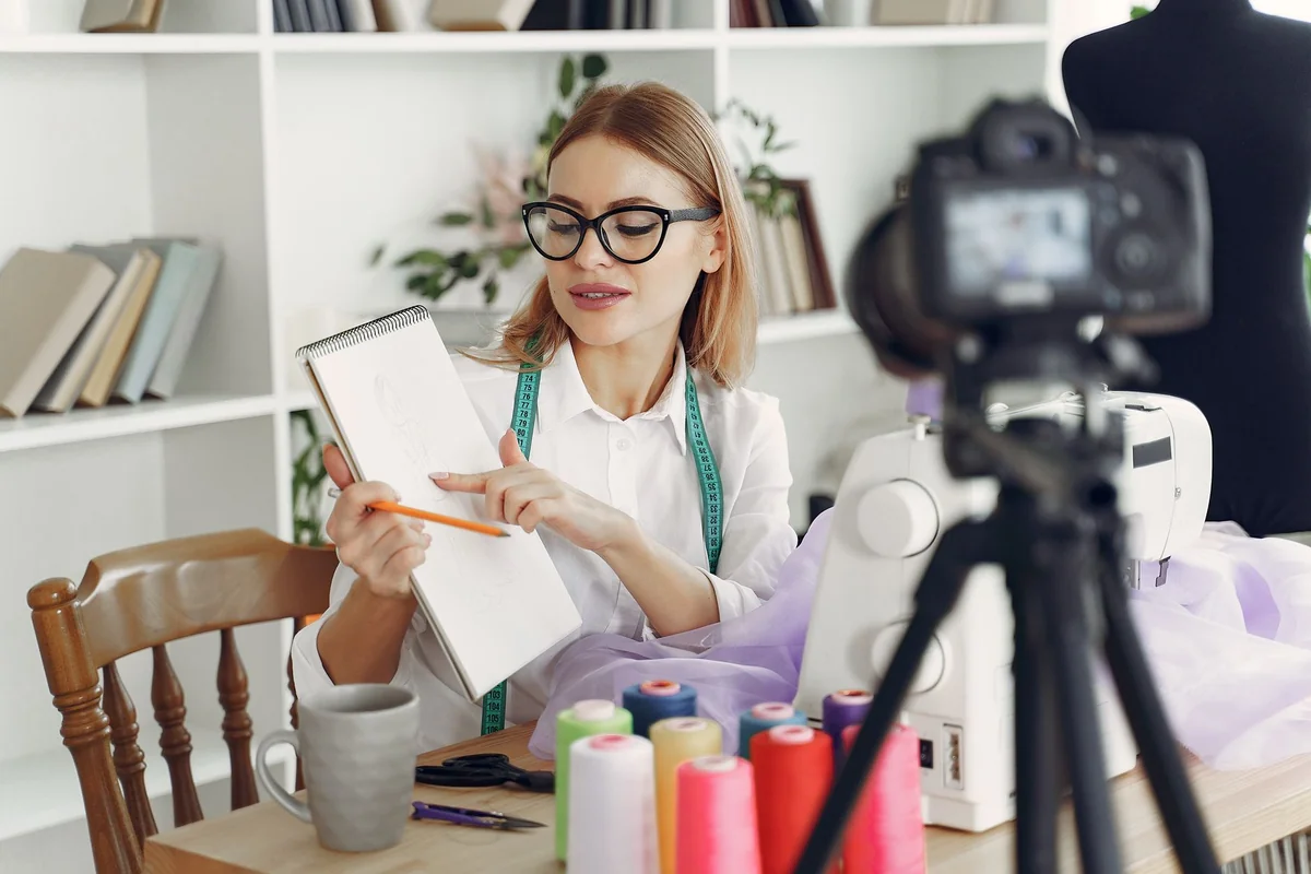 A fashion designer reviews sketches while working on a sewing project in a moder